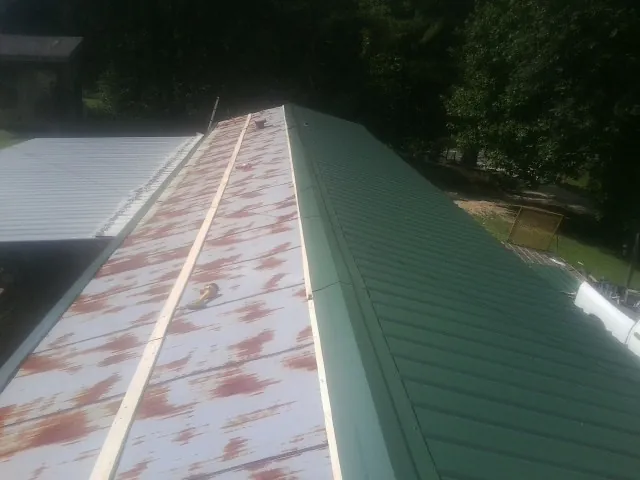Old rusted panels beside newly installed green metal roofing — Wind Damage Roof Repair by Roofing Brothers in Circleville