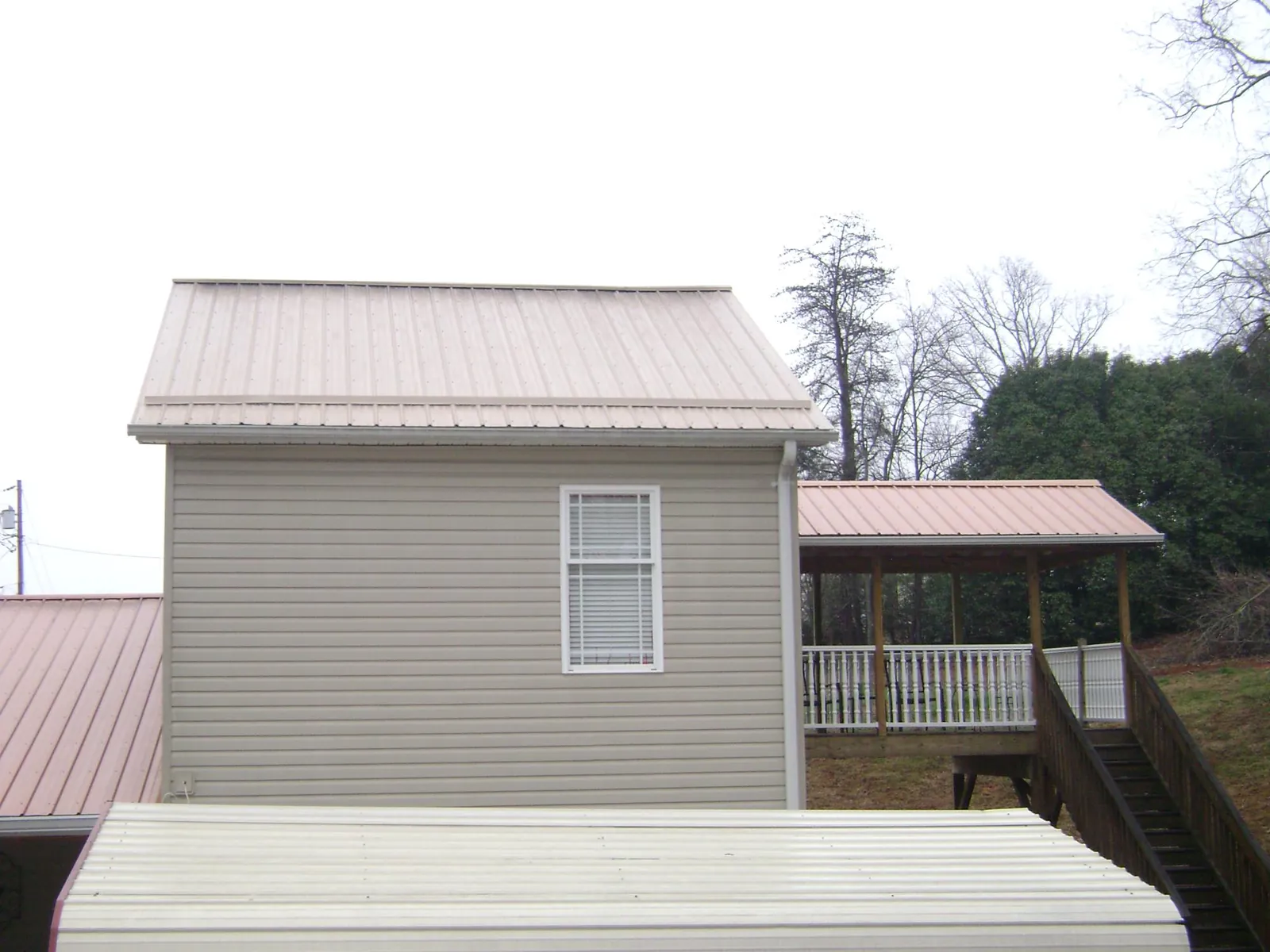 Tan metal roofs on a two story addition and attached porch, from a Roof Replacement job in Circleville