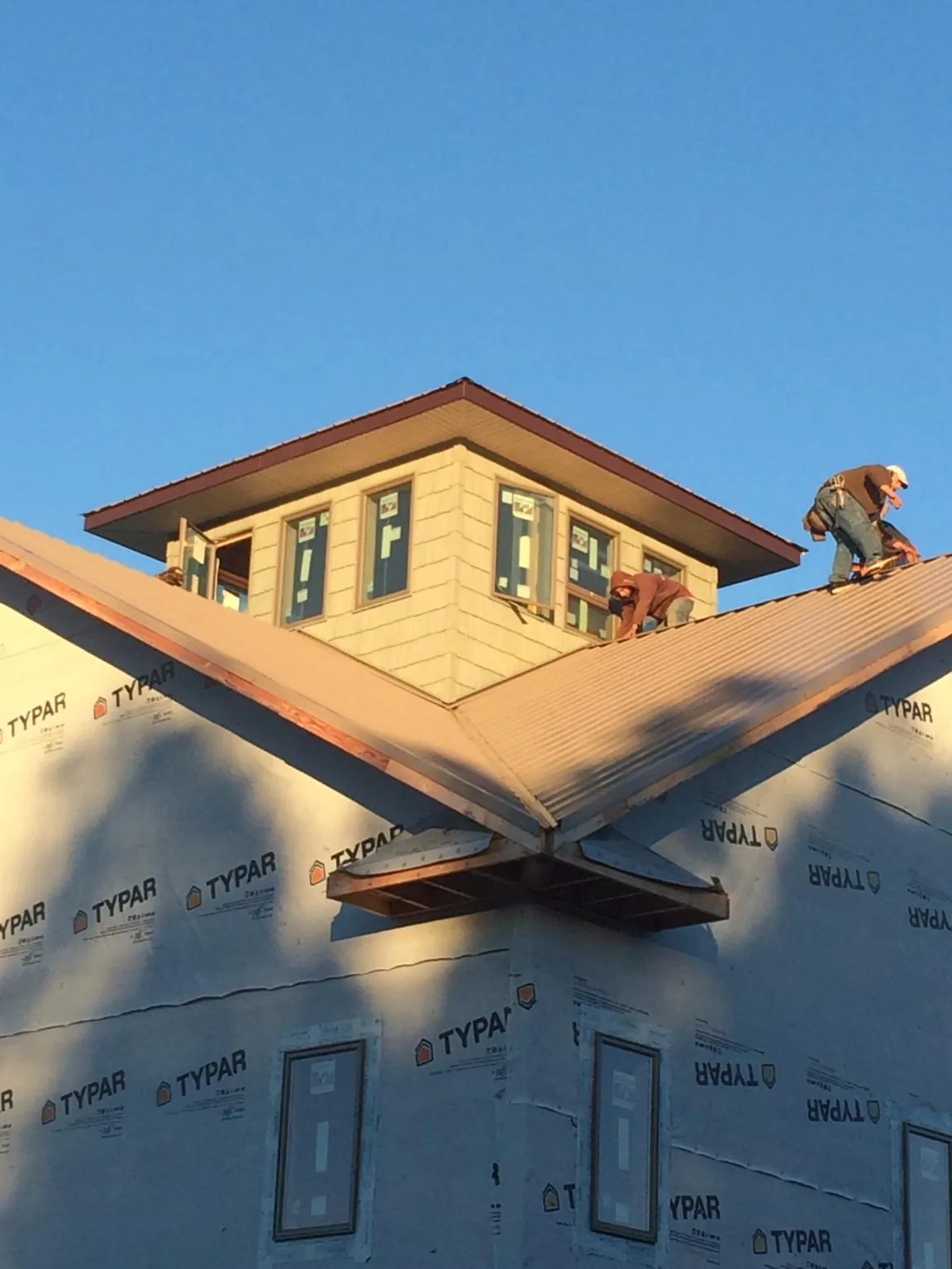 Roofers working around a rooftop cupola on a new metal roof at sunset — Roof Waterproofing in Circleville by Roofing Brothers